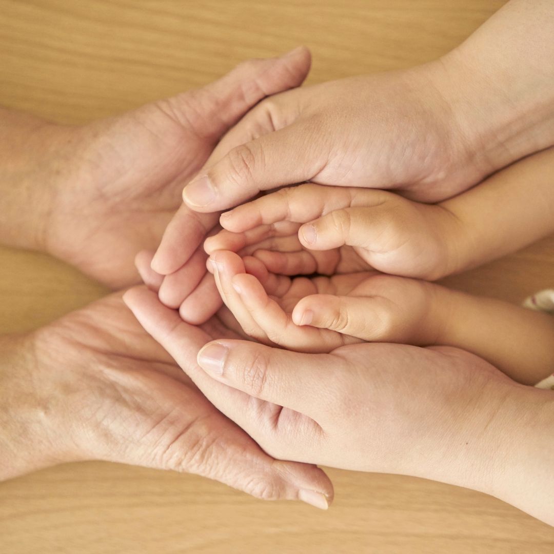 Stacked hands of adults and a child symbolising multi-generational wealth stewardship and the long-term horizon of family offices.
